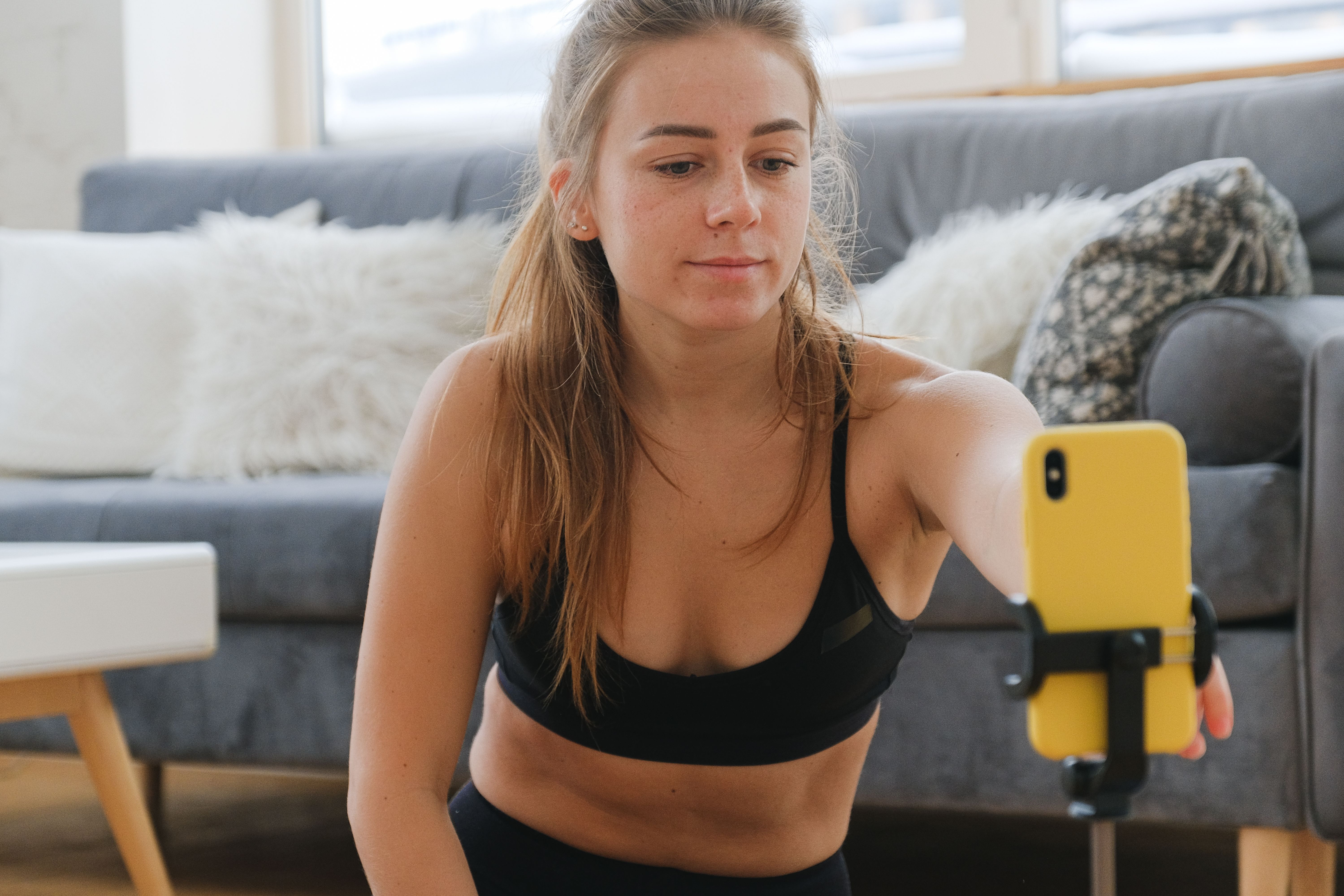 Young woman recording a smartphone video on a tripod, representing short-form social content creation for Instagram and TikTok.